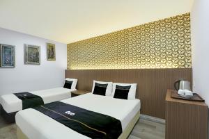 a hotel room with two beds and a wall at Dancenter Hotel Shah Alam in Shah Alam