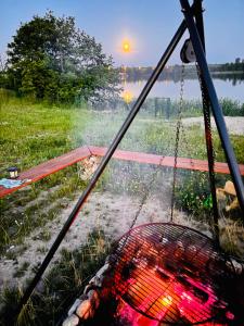 a hammock with a grill in front of a lake at New Generation Camp in Siedliska