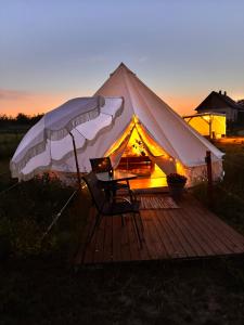 a tent with a table and chairs on a wooden deck at New Generation Camp in Siedliska