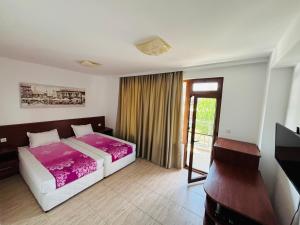 a bedroom with a bed and a desk and a window at Къща за гости Теодора in Tsarevo