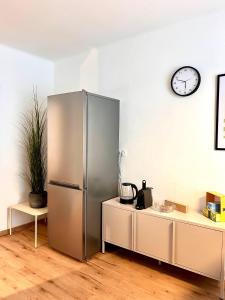 a stainless steel refrigerator and a clock on a wall at Mountain Nest Apartment in Schottwien
