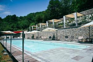 a swimming pool with umbrellas and a stone building at Old Village Linda - Tra Lunigiana & Cinque Terre in Comano