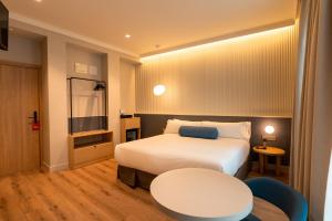 a hotel room with a white bed and a table at Petit Palace Plaza España in Madrid