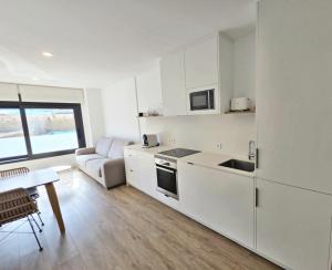 a kitchen with white cabinets and a table and a couch at BR Silgar Suites in Sanxenxo