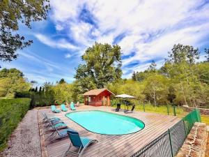 a pool on a wooden deck with chairs and a gazebo at Les frênes in Cussac