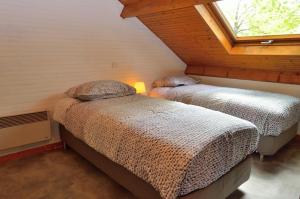 two beds in a attic bedroom with a window at Les frênes in Cussac +29 photos