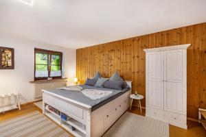 a bedroom with a white bed and wooden walls at Apartment Gardenview in Kinsau