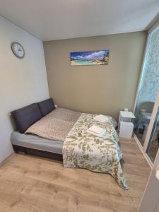 a bedroom with a bed and a clock on the wall at Sunrise Apartments 9 in Juodkrantė