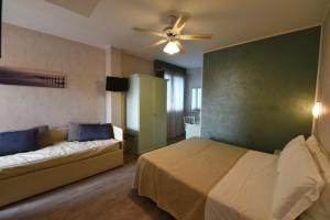 a bedroom with a bed and a couch and a fan at New Automatic Villa Daniela in San Bartolomeo al Mare