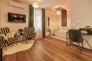 a living room with chairs and a table and a tub at Hotel Zenubia in Hajdúszoboszló