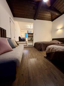 a room with two beds in a room with wooden floors at Hatoya in Mitoyo