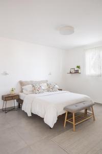 a white bedroom with a large bed and a table at לגעת בלב in Yavneʼel