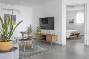 a living room with a table and a tv on a wall at לגעת בלב in Yavneʼel