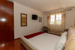 ein Schlafzimmer mit einem Bett und einem Fernseher an der Wand in der Unterkunft Hotel Platea in Shkodra