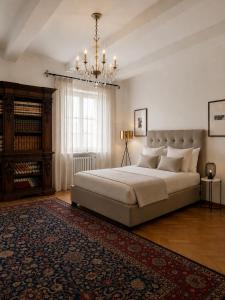 a bedroom with a large bed and a chandelier at ComeCasa No ZTL Alfieri Urban Stay in Asti +17 photos