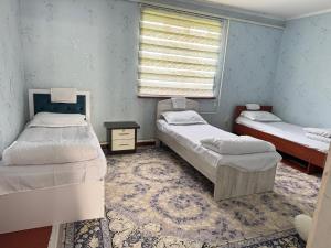 a room with three beds and a window at Hostel Hanysha in Kazarman +6 photos