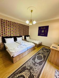 a bedroom with two beds and a rug at Mashhur in Bukhara +50 photos