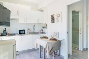 a kitchen with white cabinets and a table with chairs at Apartment Pink Vistalegre in Torrevieja