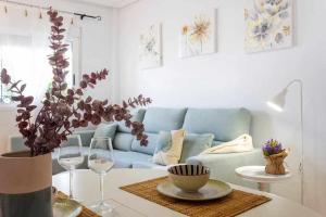 a living room with a couch and a table with wine glasses at Bungalow Pink Punta Prima in Alicante
