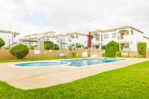 a house with a swimming pool in front of a yard at Bungalow Pink Punta Prima in Alicante