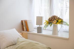 a bedroom with a window with a vase of flowers on a shelf at Döbrögi Wellness Vendégház in Nemesvita