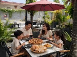 a family sitting at a table eating pizza at Tam duc villa in Tây Ninh