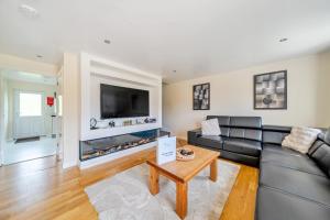 a living room with a black leather couch and a fireplace at Charcoal Lodge in Brigg
