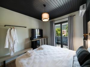 a bedroom with a white bed and a balcony at Salty Dog Suites in Vasiliki
