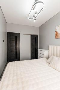 a white bedroom with a large bed and a chandelier at Modern Canadian Style Unit in Tashkent
