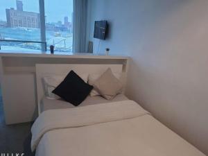 a white bed with a black pillow and a window at Birmingham Central NewStreet 1Bed in Birmingham