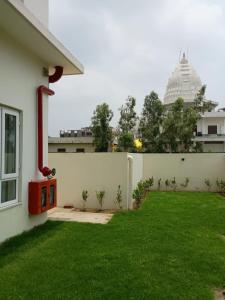 a yard with a white wall and a green lawn at Metta Shaanti Hotel Shravasti in Khargupur