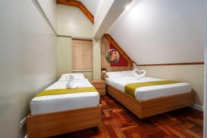 two beds in a small room with wooden floors at Highland Nest in Baguio