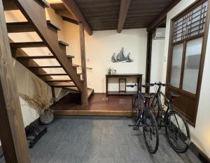 two bikes parked in a room with a staircase at Hatoya in Mitoyo