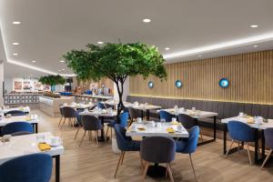 a restaurant with white tables and blue chairs at Aston Inn Lumajang - East Java in Lumajang