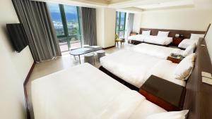 a hotel room with three beds and a large window at Formosan Naruwan Hotel in Taitung City