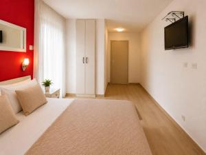 a bedroom with a bed and a television on a wall at Apartments Taida in Dobra Voda