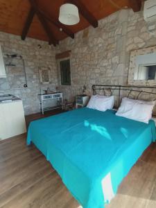 a bedroom with a blue bed in a stone wall at Villa Lydia in Meganisi +80 photos