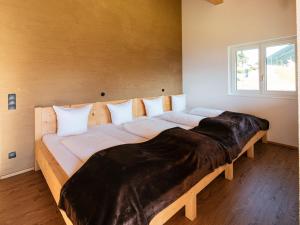 a large wooden bed in a room with a window at Alpenpanorama Konzett Faschina in Fontanella