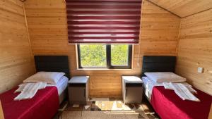 two beds in a room with wooden walls and a window at Guest House Ugra in Barskoon +141 photos