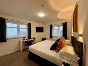 ein Schlafzimmer mit Bett, Schreibtisch und Fenstern in der Unterkunft Sarum Apart-Hotel in Saint Helier Jersey + 57 Fotos