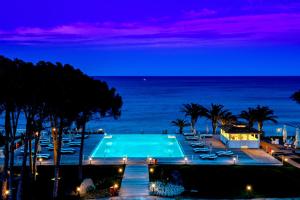 卡斯蒂亞達斯的住宿－La Villa Del Re - Adults Only - Small Luxury Hotels of the World，一个带椅子的游泳池,晚上则享有海景