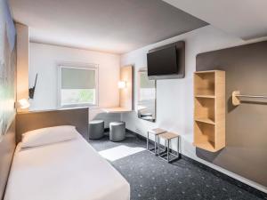 a hotel room with a bed and a tv at B&B HOTEL Düren in Düren - Eifel