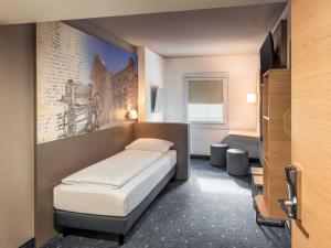 a bedroom with a bed and a painting on the wall at B&B HOTEL Düren in Düren - Eifel