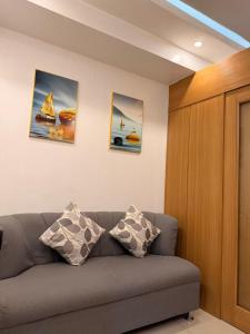 a living room with a couch and three paintings on the wall at Shell Residences MOA by Jersey in Manila