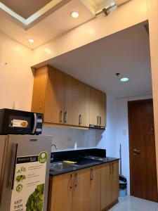 a kitchen with wooden cabinets and a refrigerator at Shell Residences MOA by Jersey in Manila +13 photos