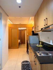 a kitchen with a black counter top and wooden cabinets at Shell Residences MOA by Jersey in Manila