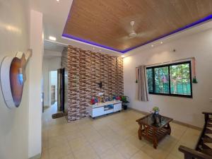 a living room with a brick wall and a table at Trupti Villa & Cottages-Nagaon- Three BHK Villa in Alibaug