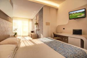 a hotel room with a bed and a television on the wall at Hotel Le Palme - Premier Resort in Milano Marittima