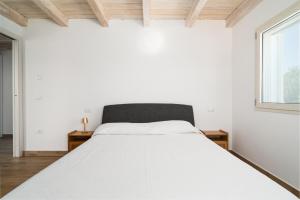 a white bedroom with a bed and a window at Villa Piricone in Orosei