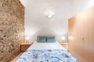 a bedroom with a bed and a stone wall at Monte Corte Enchária in São Teotónio +69 photos